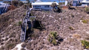 A beachfront property with a staircase leading to a house, surrounded by dry grass and sparse vegetation. - Private Beach Front: Rustic Dune Retreat (St. Augustine)