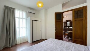 Een slaapkamer met een groot bed, een houten garderobe en een deur naar een keuken.