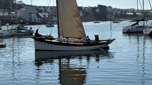 Un voilier baptisé « JEAN MOULIN » était amarré dans une marina où l’eau était calme et le ciel dégagé.