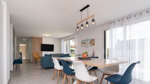 Un espace repas moderne avec une table en bois, des chaises bleues et blanches, et un luminaire suspendu.