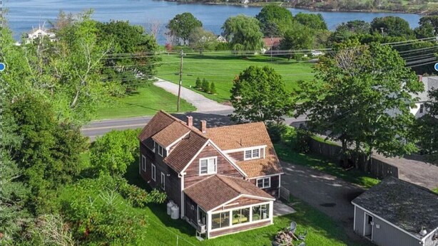 A two-story house with a large front porch, a garage, and a lawn.