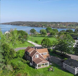 A two-story house with a large front porch, a garage, and a lawn. - Ocean View, minutes from downtown Rockland, sleeps 7 (Owls Head)