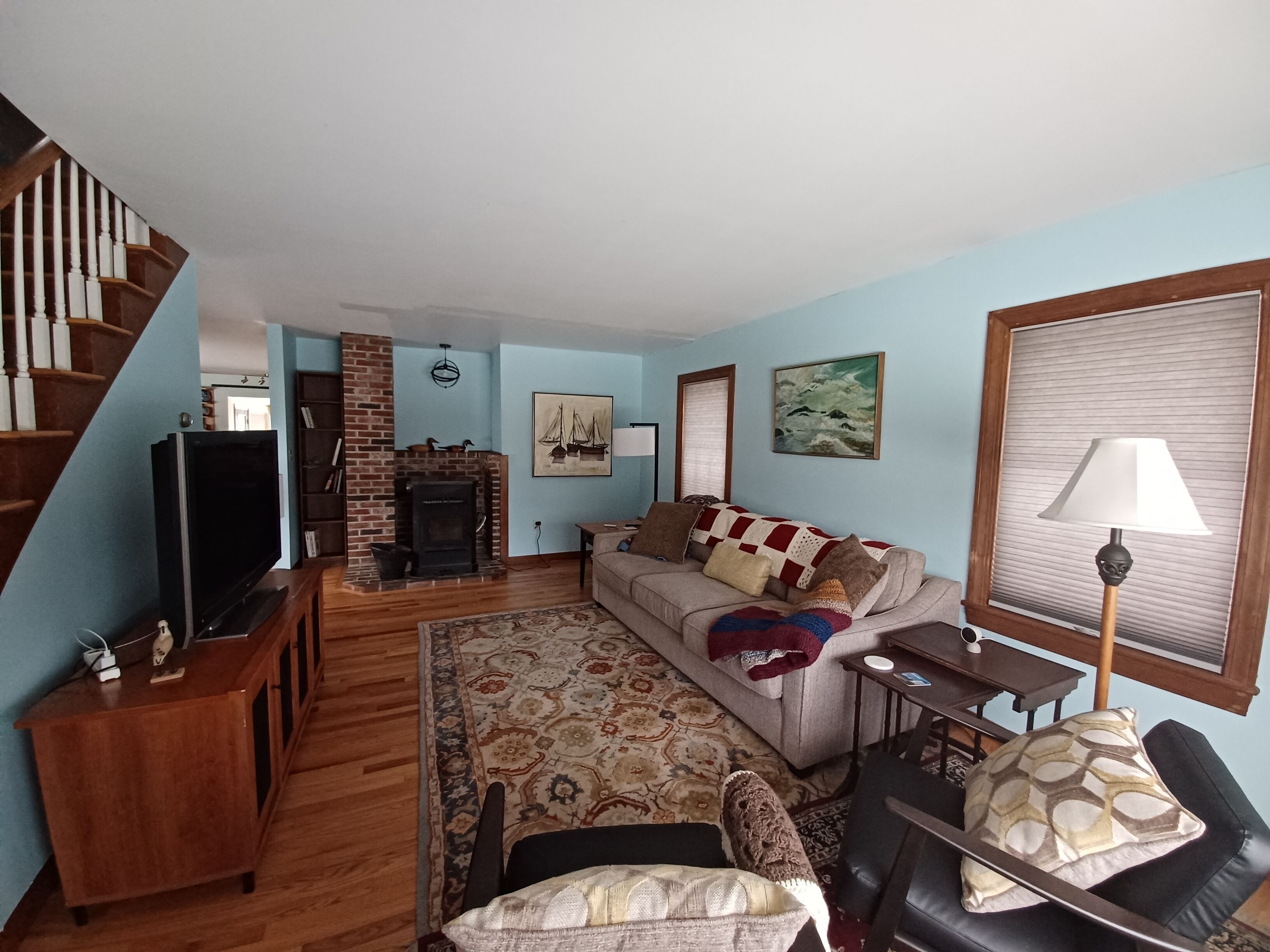 Una sala de estar con chimenea, un sofá, un televisor y una escalera.
