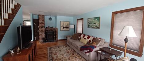 Una sala de estar con chimenea, un sofá, un televisor y una escalera.