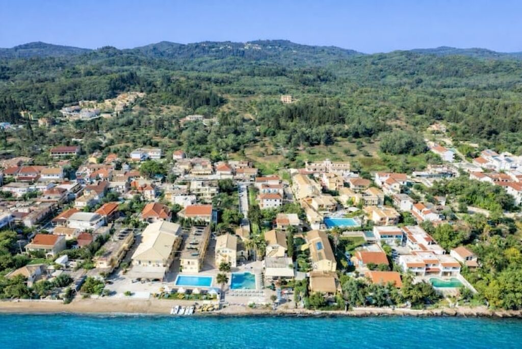 Eine Wohngegend an der Küste mit Häusern, einige davon mit Pools, und einem Strand im Vordergrund.
