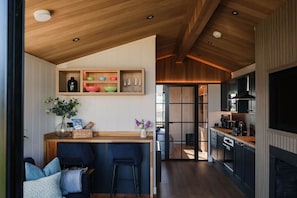 A modern kitchen with wooden cabinetry, a central island, and a dining area with bar stools.