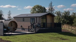 Un bâtiment moderne doté d’une façade en bois, d’un espace extérieur couvert et d’un escalier menant à une terrasse.
