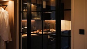 Une cuisine moderne avec des meubles de couleur sombre, un plan de travail agrémenté d’un panier à pain et un porte-manteau suspendu.