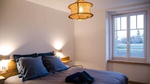 Une chambre à coucher avec un lit, des lampes de chevet, une fenêtre et un luminaire suspendu.