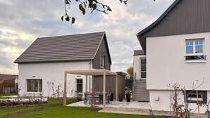Une maison moderne dotée d’un patio abrité, d’une pelouse bien entretenue et surplombée d’un ciel dégagé.
