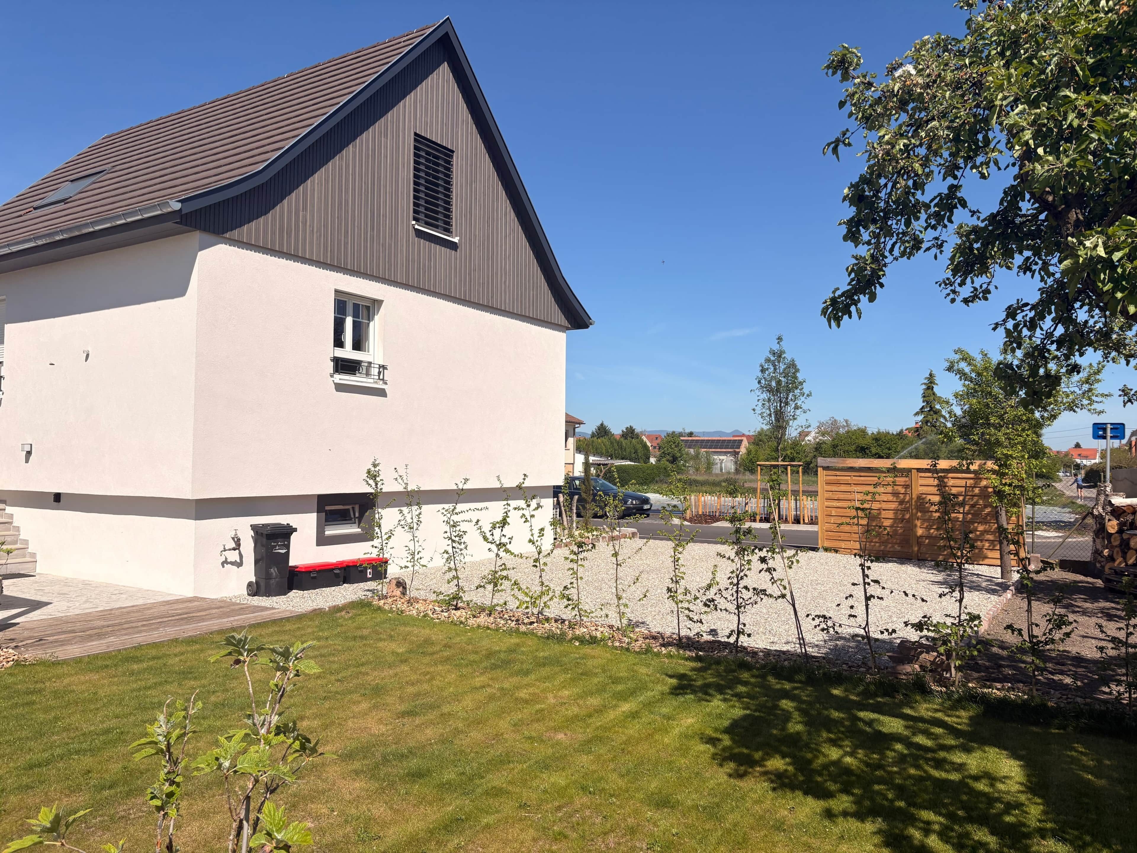 Une maison moderne à deux étages, dotée d’un toit en pente, d’une petite fenêtre et d’une porte de garage bien visible.