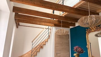 Een modern interieur met zichtbare houten balken, een wenteltrap, een houten deur en een blauwe accentmuur.