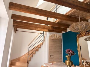 A modern interior with exposed wooden beams, a spiral staircase, a wooden door, and a blue accent wall.