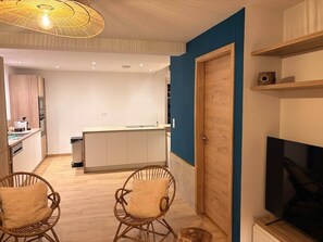 A modern kitchen with white cabinets, a wooden dining area with wicker chairs, and a blue accent wall.