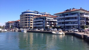 Ein Hotel am Wasser mit mehreren Gebäuden, einer Marina mit Booten und blauem Himmel.