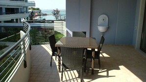 Ein Balkon mit Tisch und Stühlen, einem Blumentopf und Blick aufs Meer.