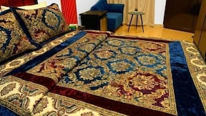 A bedroom with a large bed, a blue sofa, a small table, and a door with a paper on it. - Horus Guest House Pyramids  (Giza)