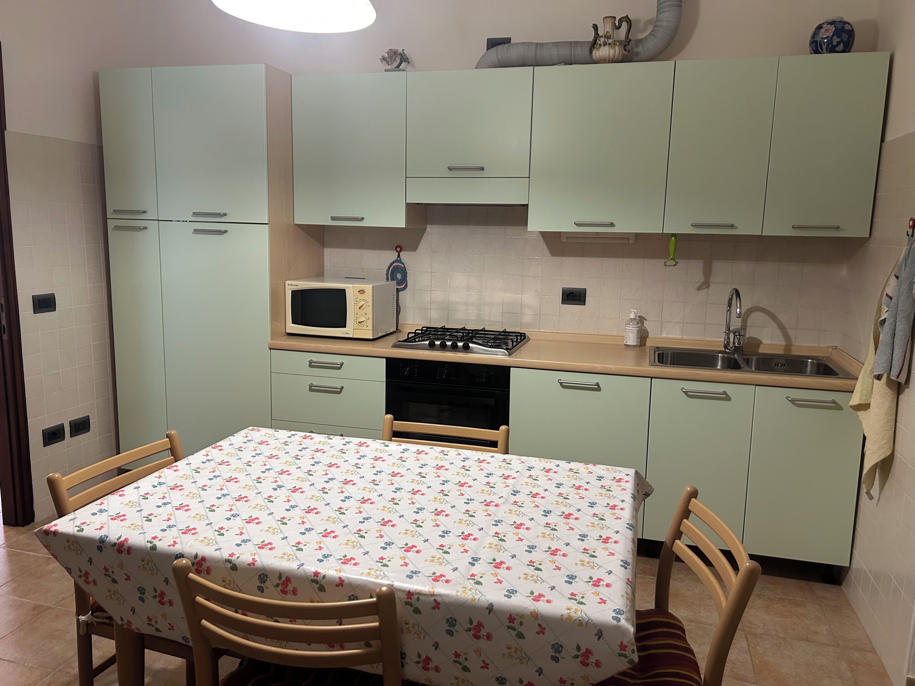 A small kitchen with a table, chairs, a microwave, a stove, and cabinets.