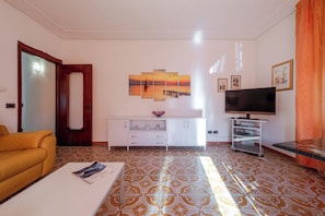 A living room with a sofa, a coffee table, a TV, a cabinet, and a patterned floor. - NEW ENTRY! COZY APARTMENT A FEW STEPS FROM THE CENTER OF LAZISE (Lazise)