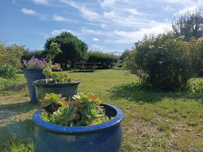 A garden with potted plants, a wooden bench, and a picnic table. - Ti Mammig. (Kerlouan)