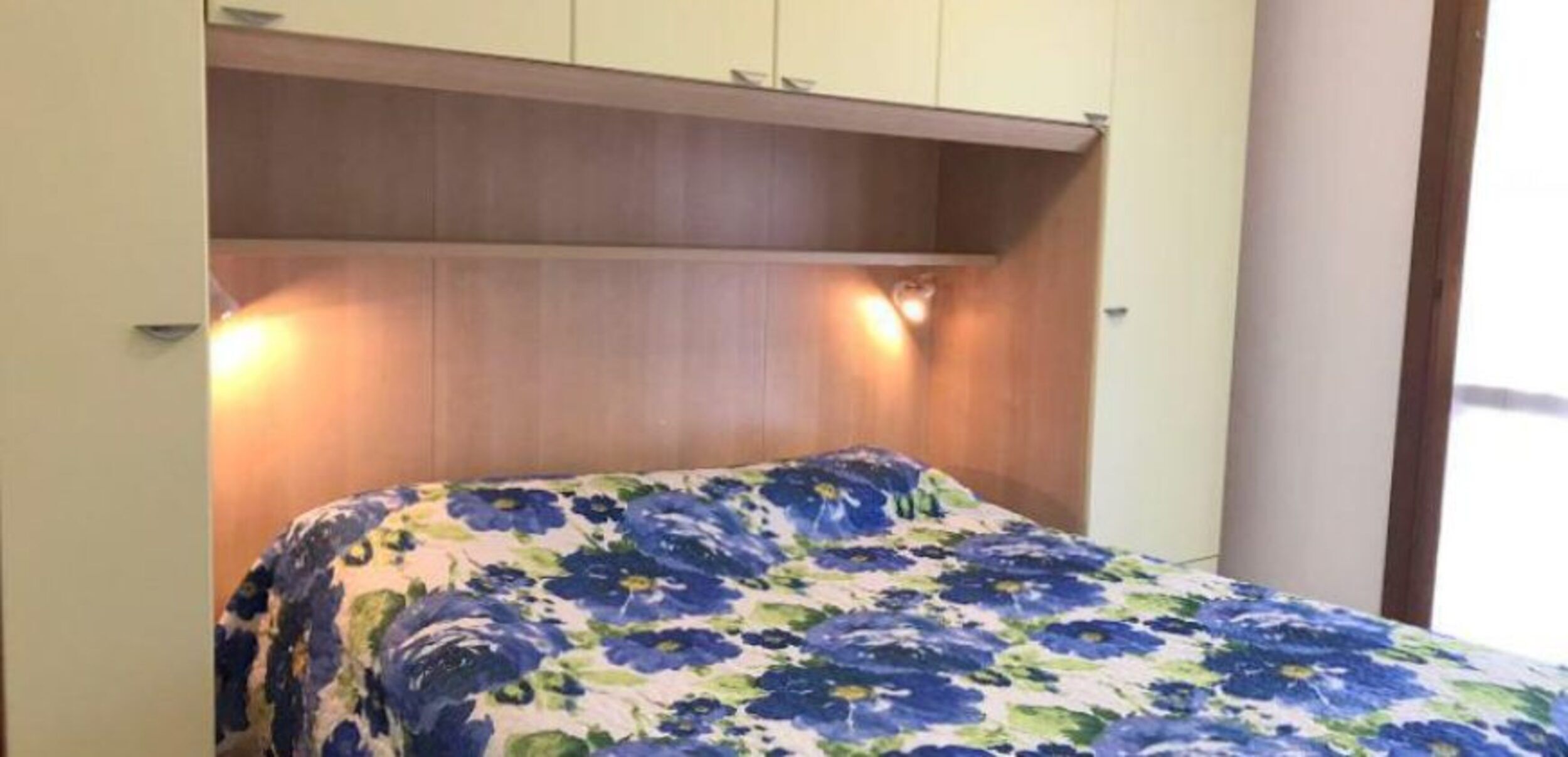 Ein Schlafzimmer mit einem Bett, einem hölzernen Kopfteil und zwei Wandleuchten.