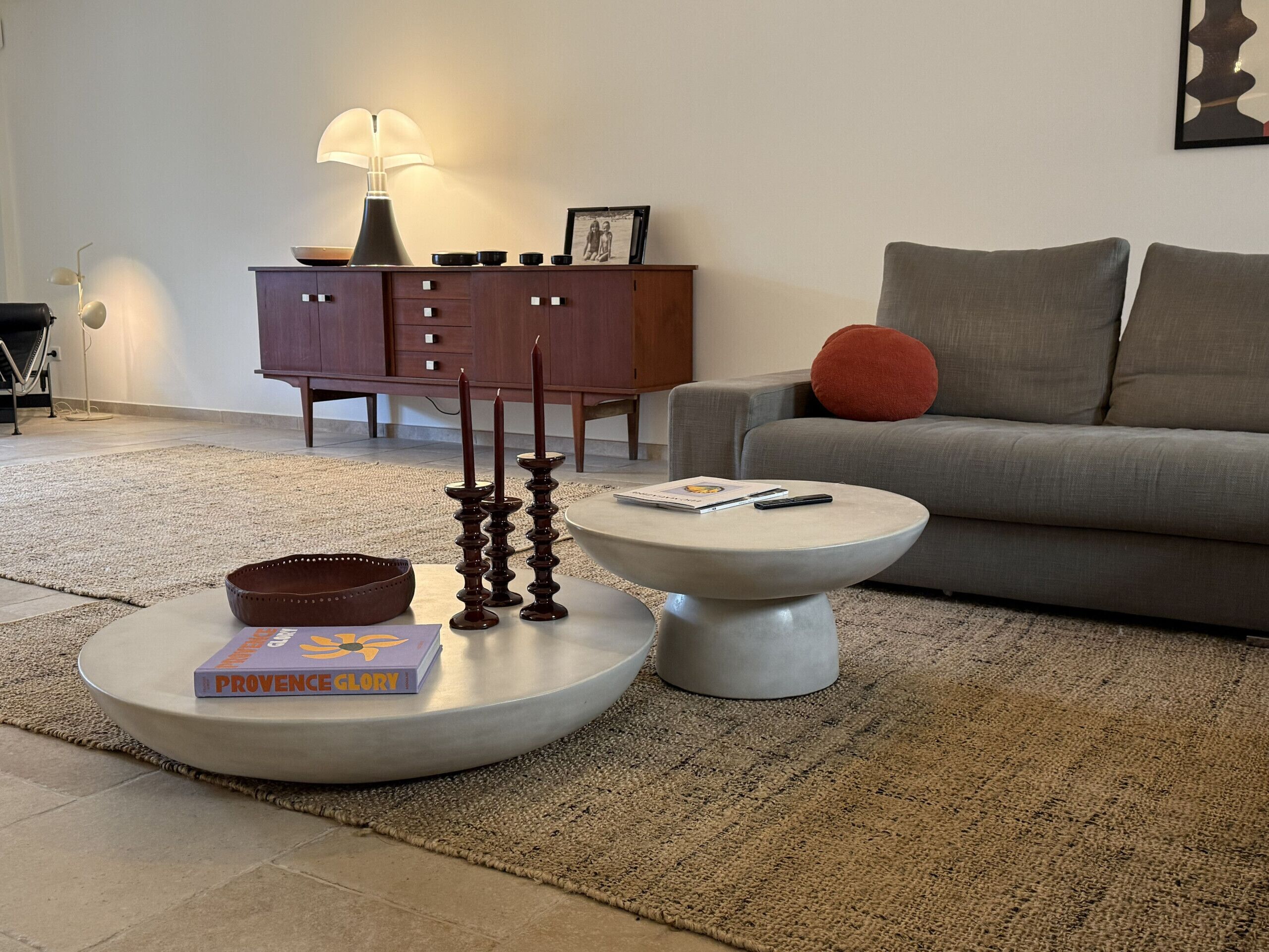 Un salon avec une table basse ronde, un canapé, une lampe et un meuble.