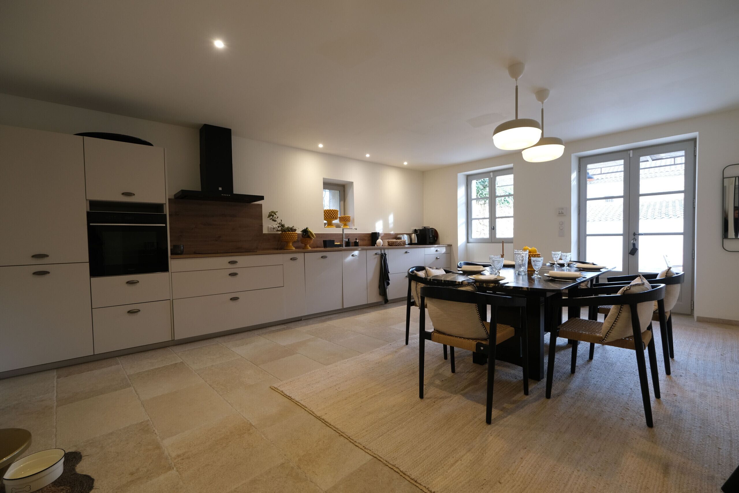 Una cucina moderna con mobili bianchi, un'isola centrale e un'area pranzo con sedie.