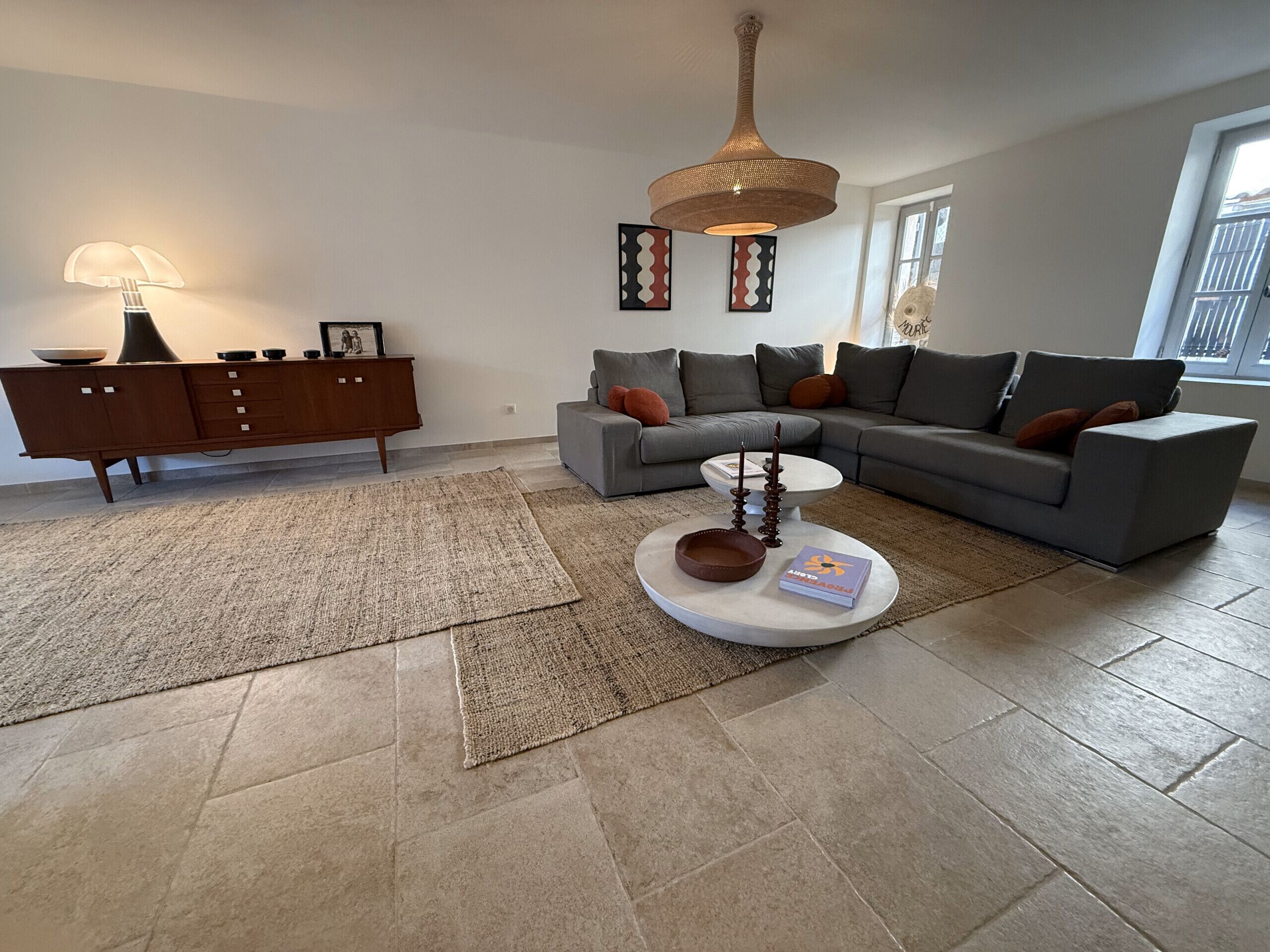Ein modernes Wohnzimmer mit einer Eckcouch, einem Couchtisch, einer Anrichte und einer Pendelleuchte.