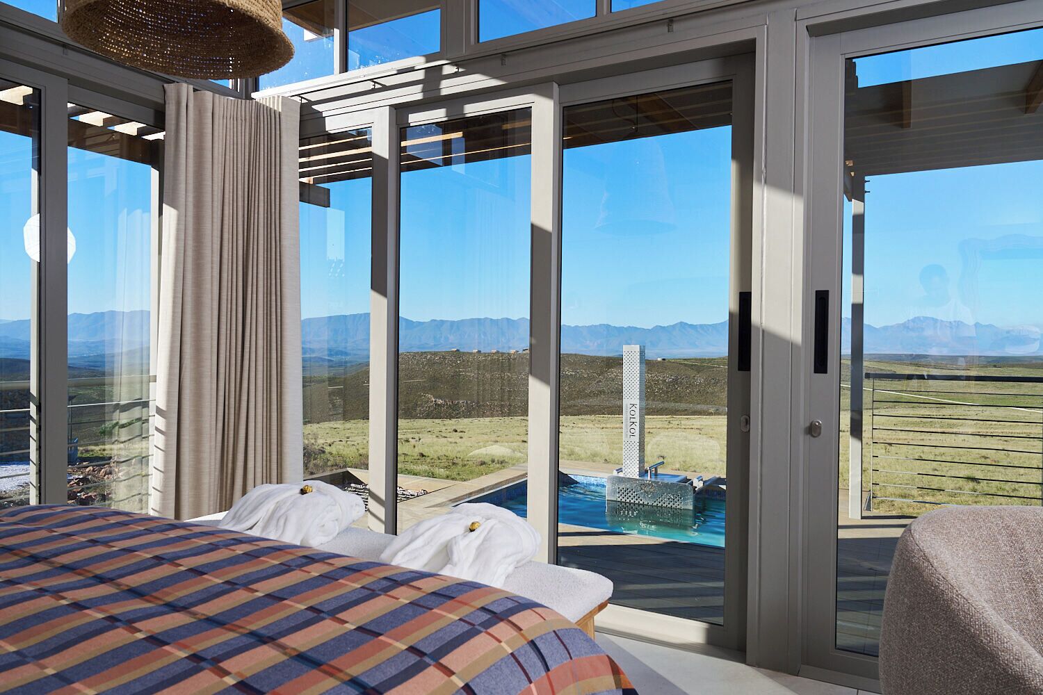 A bedroom with a large bed, a view of a pool, and a mountain landscape.