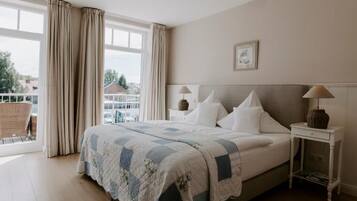 A bedroom with a large bed, a nightstand, a lamp, and a view of the outside.