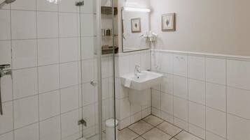 A bathroom with a glass-enclosed shower, a white sink, and a mirror above it.