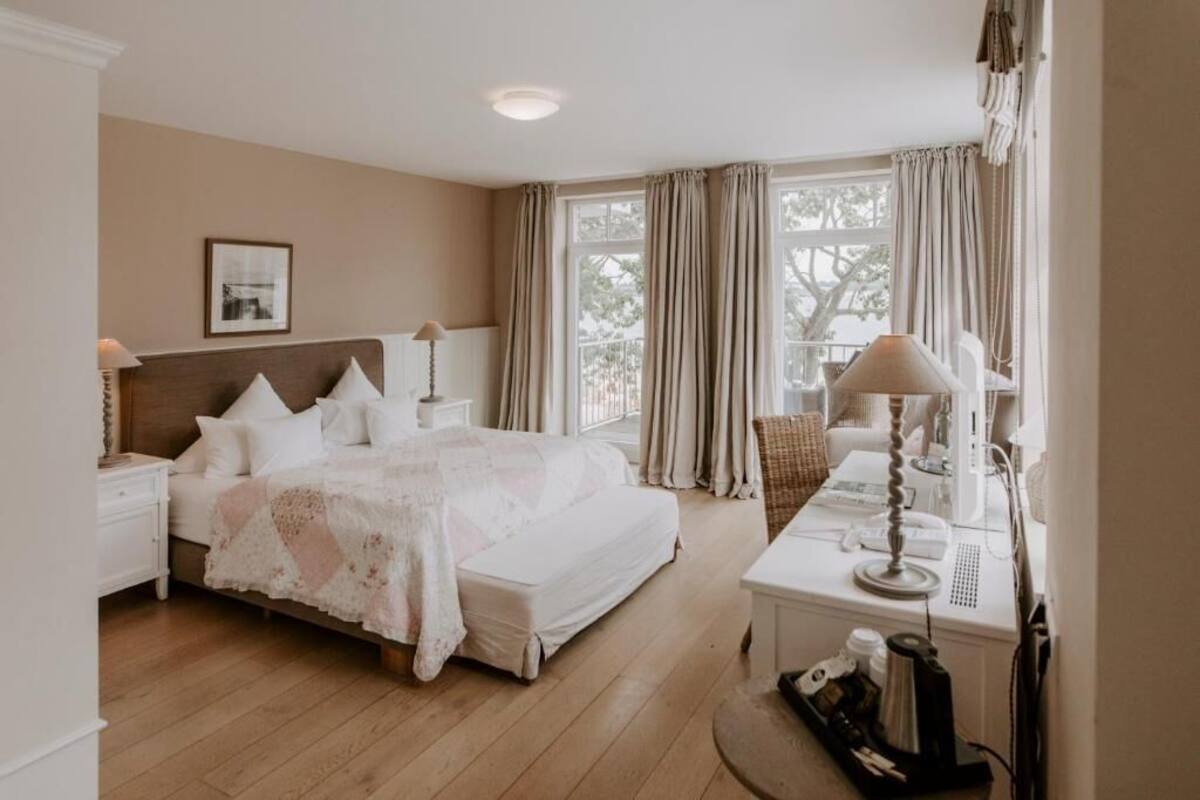 Ein Schlafzimmer mit einem großen Bett, Nachttischen, einem Schreibtisch mit Lampe und einem Fenster mit Vorhängen.