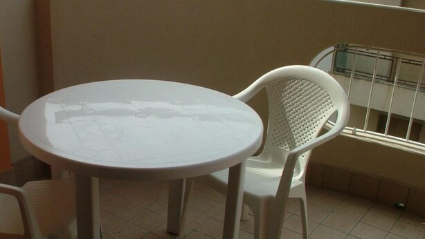 A small round table with a white tablecloth, surrounded by two white plastic chairs with perforated backs. - Family Friendly Vacation Apartment With a Balcony (Grado)