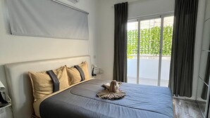 Een moderne slaapkamer met een groot bed, een ingebouwd bureau en een schuifdeur naar een balkon.