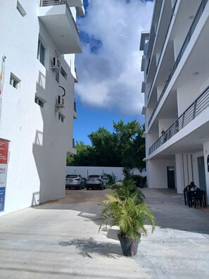 A courtyard with a potted plant, two parked cars, and a building with balconies. - La belle planque- 10 minutos de la Playa- PUNTA CANA (Punta Cana)