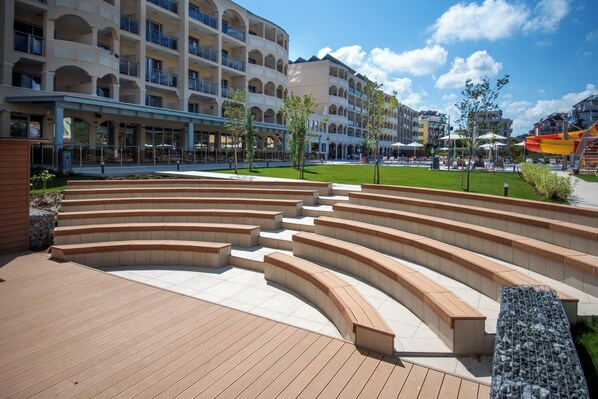 Un hotel moderno con un patio central, mobiliario exterior y zona de piscina.