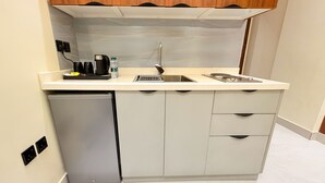 A compact kitchen with a dishwasher, a sink, and a coffee maker. - Tura Residence Al Khaleej (Riyadh)