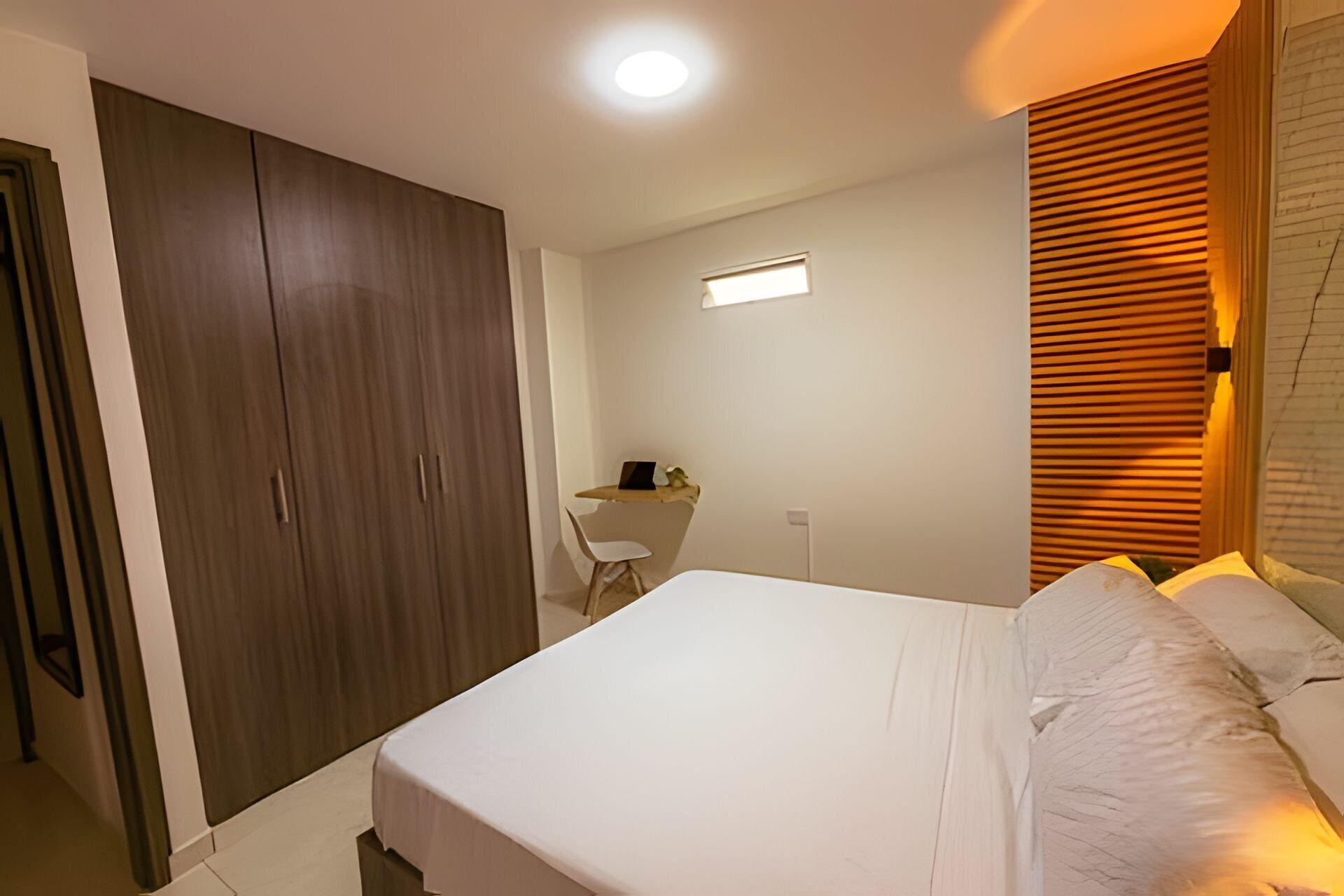 Un dormitorio con cama, escritorio y armario.