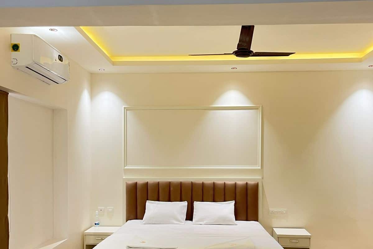 Una habitación de hotel moderna con una cama grande, cabecera, mesitas de noche y un equipo de aire acondicionado.