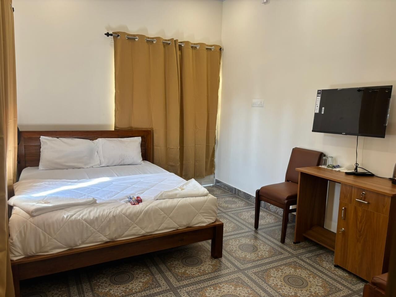 A hotel room with a bed, a desk with a computer, and a television.