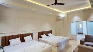 A modern hotel room with two beds, a ceiling fan, and a seating area. - aagneyam grand RESORT (Kozhikode)