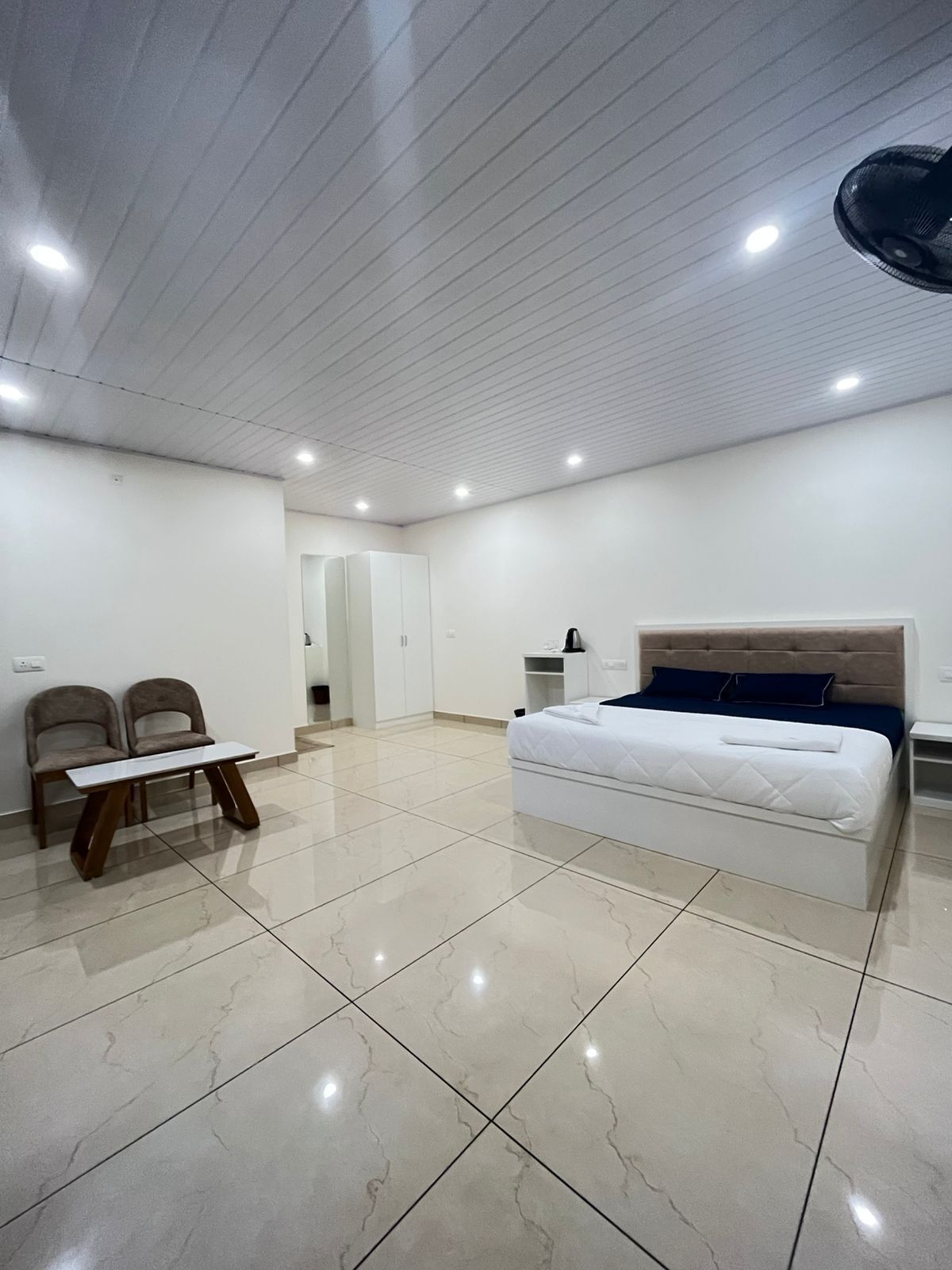 Een moderne slaapkamer met een bed, een bureau en twee stoelen.