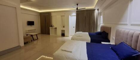 A hotel room with two beds, a TV, a desk, and a bathroom in the background.