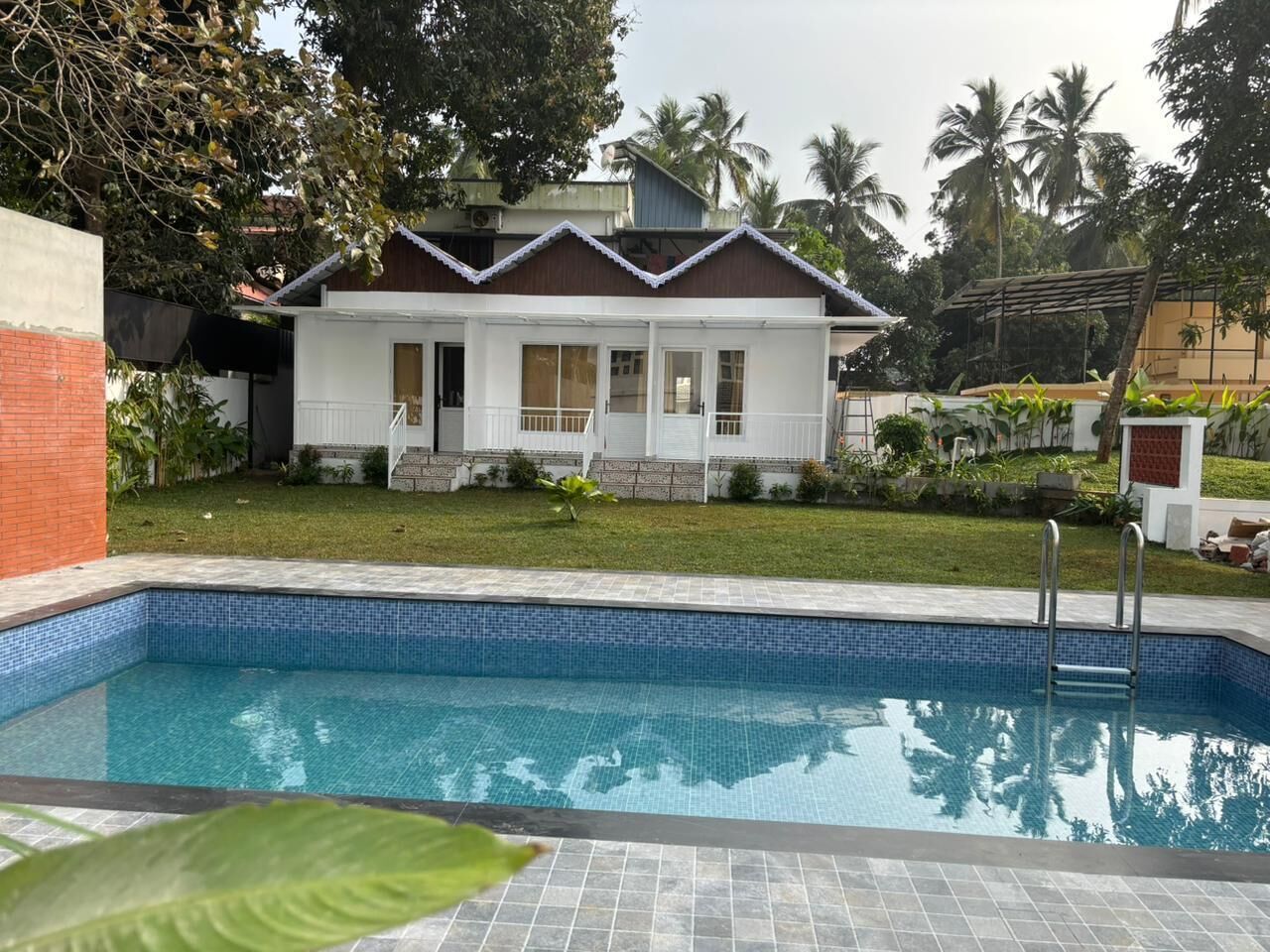 Una piscina con una casa blanca al fondo.