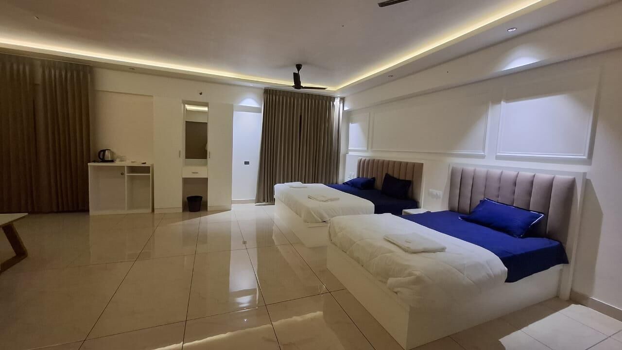 A hotel room with two beds, a desk, a mirror, and a bathroom.