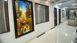 Un pasillo de hotel con obras de arte enmarcadas, piso a cuadros y un muro espejado.