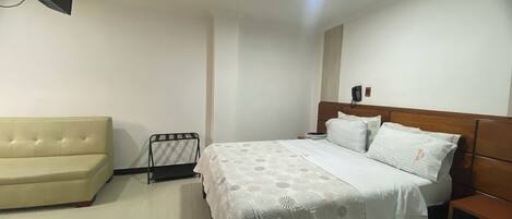 Une chambre à coucher comprenant un lit, un canapé, une table de chevet et un téléphone fixé au mur.
