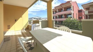 A balcony with a table and chairs, a tiled floor, and a view of neighboring buildings. - Sweet Holiday Hideaway in Grado for Four Guests (Grado)