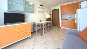 A compact living space with a kitchenette, a dining area, and a seating area. - Sweet Holiday Hideaway in Grado for Four Guests (Grado)