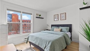 Une chambre à coucher avec un lit, une fenêtre, un bureau et une chaise.